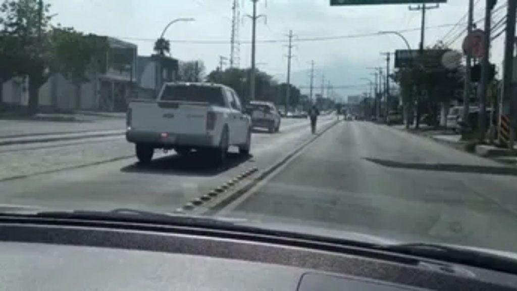 View from a Car: a White Pickup in the Left Lane Ahead, Cyclist in the Center of the Road on an Urban Street. • Guadalupe Informa