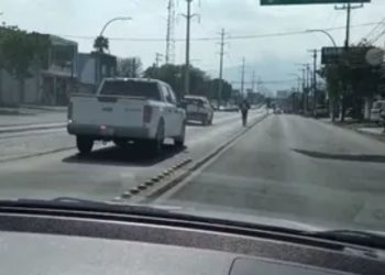 View from a Car: a White Pickup in the Left Lane Ahead, Cyclist in the Center of the Road on an Urban Street. • Guadalupe Informa