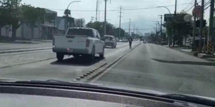 View from a Car: a White Pickup in the Left Lane Ahead, Cyclist in the Center of the Road on an Urban Street. • Guadalupe Informa